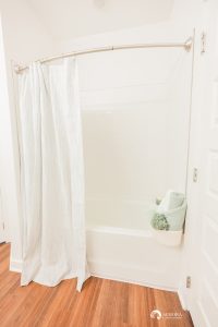 A modern bathroom in Apartments in Ocala featuring a white shower curtain and wooden floors.