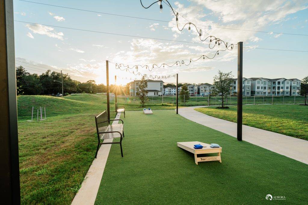 A park in Ocala with benches and a corn hole game, perfect for residents of nearby apartments.