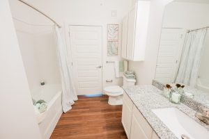 Apartments for rent in Ocala A brightly lit, modern bathroom in apartments for rent in Ocala with a white color scheme featuring a bathtub, toilet, sink, and cabinets with wood flooring. Aurora St. Leon Apartments in Ocala 2150 NW 21st Avenue | Ocala, FL 34475 (352) 233-4133