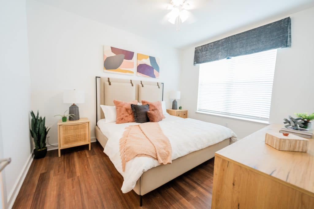 Apartments for rent in Ocala Modern bedroom with a neatly made bed, abstract wall art, and hardwood floors. Aurora St. Leon Apartments in Ocala 2150 NW 21st Avenue | Ocala, FL 34475 (352) 233-4133