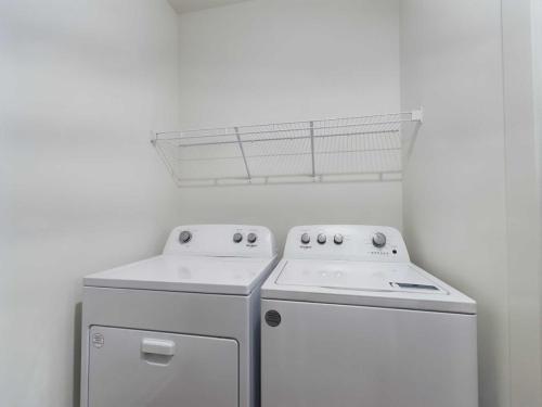 Apartments for rent in Ocala A laundry room with a white washer and dryer set beneath a white wire shelf on a light-colored wall. Aurora St. Leon Apartments in Ocala 2150 NW 21st Avenue | Ocala, FL 34475 (352) 233-4133