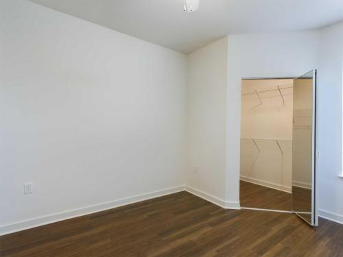 Apartments for rent in Ocala An empty room with white walls, wooden flooring, and an open door revealing a small walk-in closet with wire shelving. Aurora St. Leon Apartments in Ocala 2150 NW 21st Avenue | Ocala, FL 34475 (352) 233-4133