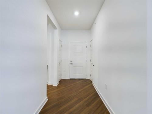 Apartments for rent in Ocala A hallway with white walls, a wooden floor, and three closed white doors. The hallway is well-lit by a ceiling light. Aurora St. Leon Apartments in Ocala 2150 NW 21st Avenue | Ocala, FL 34475 (352) 233-4133