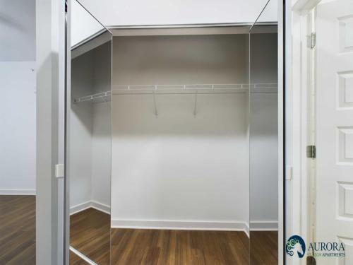 Apartments for rent in Ocala An empty walk-in closet with a wooden floor, white walls, a wire shelf, and sliding mirrored doors, located in Aurora Beacon Apartments. Aurora St. Leon Apartments in Ocala 2150 NW 21st Avenue | Ocala, FL 34475 (352) 233-4133