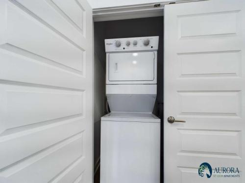 Apartments for rent in Ocala A white stacked washer and dryer unit is installed in a closet with white doors. The closet is part of an apartment at Aurora Stelton Apartments, as indicated by the logo on the lower right. Aurora St. Leon Apartments in Ocala 2150 NW 21st Avenue | Ocala, FL 34475 (352) 233-4133