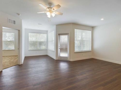 Apartments for rent in Ocala A vacant room with wooden floors, a ceiling fan, large windows, and a glass door leading outside. Aurora St. Leon Apartments in Ocala 2150 NW 21st Avenue | Ocala, FL 34475 (352) 233-4133