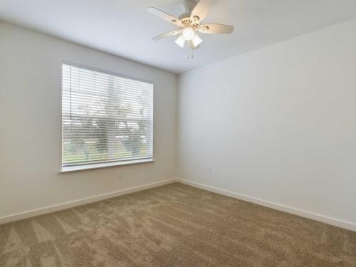 Apartments for rent in Ocala An empty room with beige carpet, a window with blinds, and a ceiling fan with lights. Aurora St. Leon Apartments in Ocala 2150 NW 21st Avenue | Ocala, FL 34475 (352) 233-4133