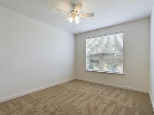 Apartments for rent in Ocala An empty room with beige carpet, white walls, a ceiling fan with light, and a window with white blinds. Aurora St. Leon Apartments in Ocala 2150 NW 21st Avenue | Ocala, FL 34475 (352) 233-4133