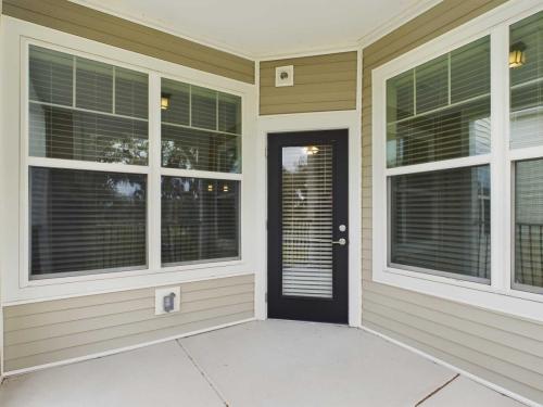 Apartments for rent in Ocala Enclosed patio area with three large windows and a single door, all with blinds, in a corner of a building with beige siding. Aurora St. Leon Apartments in Ocala 2150 NW 21st Avenue | Ocala, FL 34475 (352) 233-4133