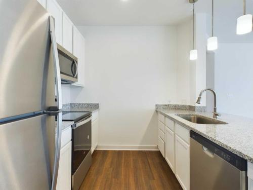 Apartments for rent in Ocala Modern kitchen with stainless steel appliances including a refrigerator, oven, and dishwasher. White cabinets, granite countertops, and pendant lights. Hardwood flooring throughout. Aurora St. Leon Apartments in Ocala 2150 NW 21st Avenue | Ocala, FL 34475 (352) 233-4133