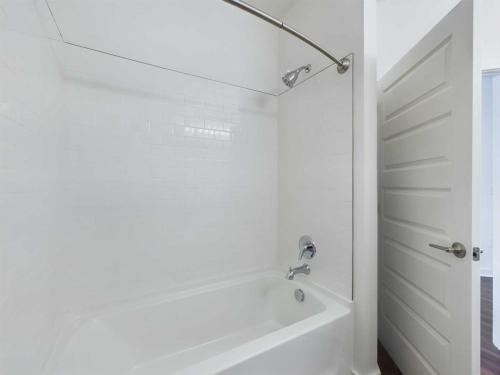 Apartments for rent in Ocala Image showing a white bathtub with a curved shower curtain rod and white tile walls. The door to the bathroom is partway open. Aurora St. Leon Apartments in Ocala 2150 NW 21st Avenue | Ocala, FL 34475 (352) 233-4133