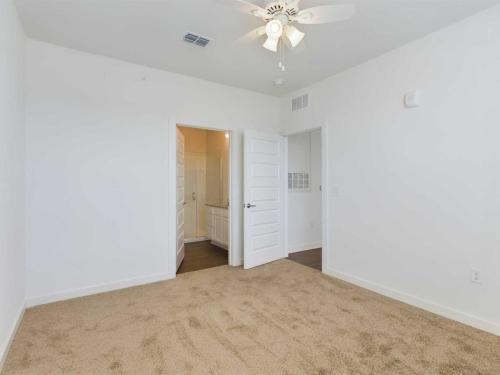 Apartments for rent in Ocala A clean, empty room with white walls, beige carpet, ceiling fan, and open door leading to a hallway. Aurora St. Leon Apartments in Ocala 2150 NW 21st Avenue | Ocala, FL 34475 (352) 233-4133
