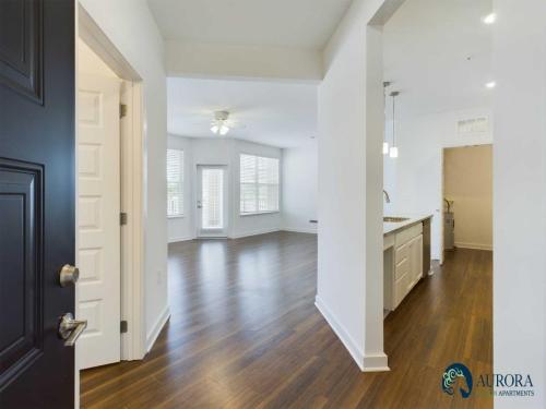 Apartments for rent in Ocala A modern apartment interior featuring a spacious living area with hardwood floors, open kitchen with white cabinetry and countertops, and large windows providing ample natural light. Aurora St. Leon Apartments in Ocala 2150 NW 21st Avenue | Ocala, FL 34475 (352) 233-4133