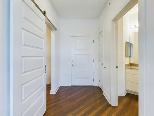 Apartments for rent in Ocala An entryway with wooden flooring, a paneled front door, a sliding barn door, and a doorway leading to a bathroom with a granite countertop. Aurora St. Leon Apartments in Ocala 2150 NW 21st Avenue | Ocala, FL 34475 (352) 233-4133