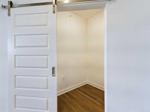 Apartments for rent in Ocala An empty closet with wooden flooring and white walls, featuring a partially open white sliding door. Aurora St. Leon Apartments in Ocala 2150 NW 21st Avenue | Ocala, FL 34475 (352) 233-4133