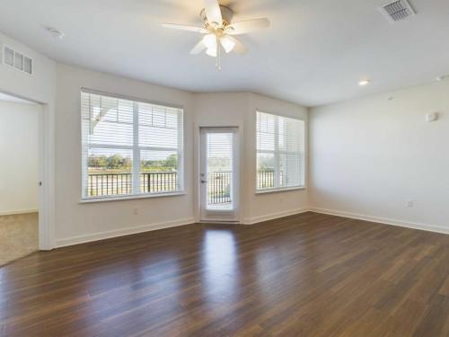 Apartments for rent in Ocala Empty room with large windows, a ceiling fan, and hardwood flooring. Sunlight streams in through the windows, and there is a door leading to an outdoor balcony. Room is painted white. Aurora St. Leon Apartments in Ocala 2150 NW 21st Avenue | Ocala, FL 34475 (352) 233-4133