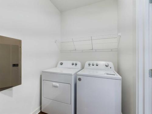 Apartments for rent in Ocala A small laundry room with a white washer and dryer set, a wire shelf above them, and an electrical panel on the left wall. Aurora St. Leon Apartments in Ocala 2150 NW 21st Avenue | Ocala, FL 34475 (352) 233-4133