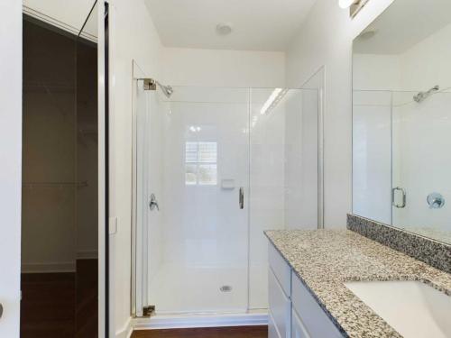 Apartments for rent in Ocala Modern bathroom with a glass-enclosed shower, white walls, granite countertop vanity, and a large mirror. Aurora St. Leon Apartments in Ocala 2150 NW 21st Avenue | Ocala, FL 34475 (352) 233-4133