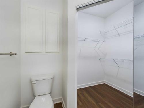 Apartments for rent in Ocala A small bathroom with a toilet beside a closet with shelves and a sliding door. The flooring is wood and the walls are white. Aurora St. Leon Apartments in Ocala 2150 NW 21st Avenue | Ocala, FL 34475 (352) 233-4133