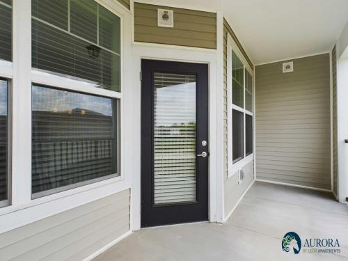 Apartments for rent in Ocala A small porch area with light beige siding, a glass door with blinds, large windows on the left, and the logo "Aurora St. Leon Apartments" in the bottom right corner. Aurora St. Leon Apartments in Ocala 2150 NW 21st Avenue | Ocala, FL 34475 (352) 233-4133