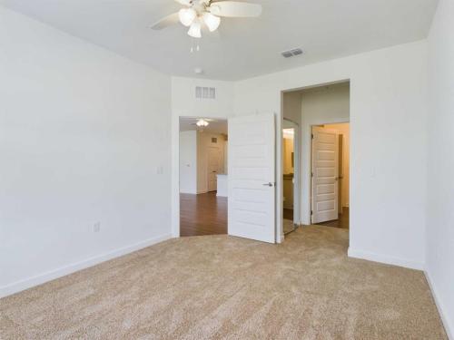 Apartments for rent in Ocala A carpeted empty room with white walls, a ceiling fan, and two open doors that lead to other parts of a house. Aurora St. Leon Apartments in Ocala 2150 NW 21st Avenue | Ocala, FL 34475 (352) 233-4133