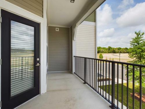 Apartments for rent in Ocala A covered balcony with a black-framed glass door, metal railing, and view of a grassy area and trees. The sky is partly cloudy. Aurora St. Leon Apartments in Ocala 2150 NW 21st Avenue | Ocala, FL 34475 (352) 233-4133