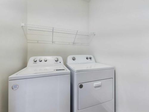Apartments for rent in Ocala A laundry room with a white washing machine and dryer side by side, beneath a wire shelf mounted on the wall. Aurora St. Leon Apartments in Ocala 2150 NW 21st Avenue | Ocala, FL 34475 (352) 233-4133