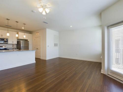 Apartments for rent in Ocala A modern, empty apartment with wooden floors, white walls, an open kitchen with stainless steel appliances, and a ceiling fan. Aurora St. Leon Apartments in Ocala 2150 NW 21st Avenue | Ocala, FL 34475 (352) 233-4133