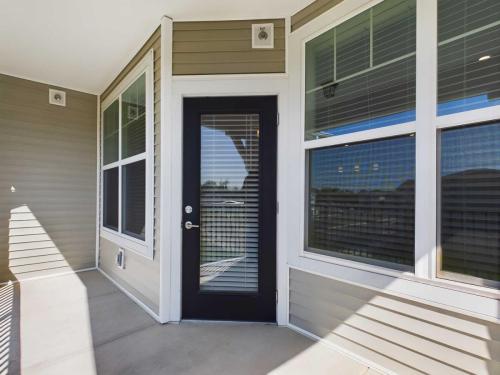 Apartments for rent in Ocala A modern house entrance with a black framed glass door and white blinds on adjacent windows, set within beige siding walls. Aurora St. Leon Apartments in Ocala 2150 NW 21st Avenue | Ocala, FL 34475 (352) 233-4133