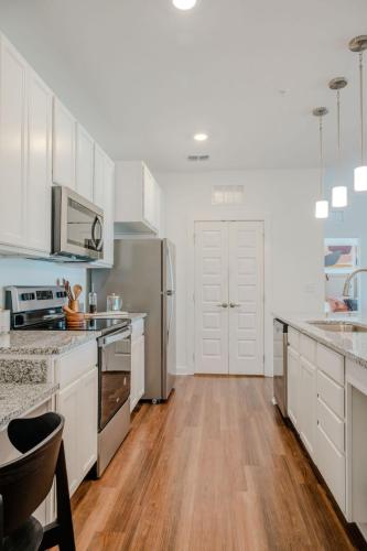Apartments for rent in Ocala Modern kitchen with stainless steel appliances, white cabinetry, granite countertops, wood flooring, pendant lighting, and a double-door pantry. Aurora St. Leon Apartments in Ocala 2150 NW 21st Avenue | Ocala, FL 34475 (352) 233-4133