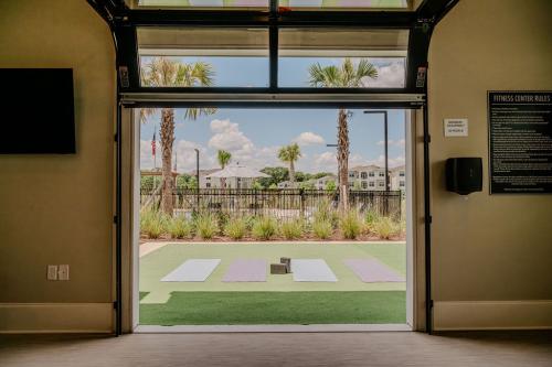 Apartments for rent in Ocala Four yoga mats are laid out on a grassy outdoor area, with palm trees and a clear blue sky in the background, seen through an open garage door of a fitness center. Aurora St. Leon Apartments in Ocala 2150 NW 21st Avenue | Ocala, FL 34475 (352) 233-4133