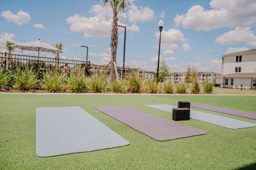 Apartments for rent in Ocala Three yoga mats and two yoga blocks are arranged on a grassy area outdoors with a clear sky and buildings in the background. Aurora St. Leon Apartments in Ocala 2150 NW 21st Avenue | Ocala, FL 34475 (352) 233-4133