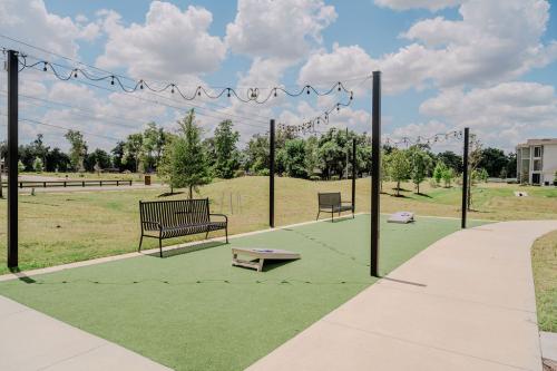Apartments for rent in Ocala Outdoor recreational area with benches, string lights, and cornhole boards on artificial turf, set under a partly cloudy sky with trees and a building in the background. Aurora St. Leon Apartments in Ocala 2150 NW 21st Avenue | Ocala, FL 34475 (352) 233-4133