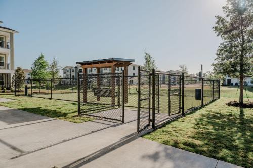 Apartments for rent in Ocala A fenced dog park with green grass, shaded benches, and trees, located in a residential area with apartment buildings in the background. Aurora St. Leon Apartments in Ocala 2150 NW 21st Avenue | Ocala, FL 34475 (352) 233-4133