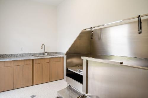 Apartments for rent in Ocala A modern veterinary examination and bathing area with stainless steel tub, wooden cabinets, countertop sink, and light-colored flooring. Aurora St. Leon Apartments in Ocala 2150 NW 21st Avenue | Ocala, FL 34475 (352) 233-4133