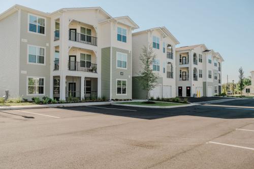 Apartments for rent in Ocala A view of three modern apartment buildings with balconies, empty parking spaces in front, and a clear blue sky in the background. Aurora St. Leon Apartments in Ocala 2150 NW 21st Avenue | Ocala, FL 34475 (352) 233-4133