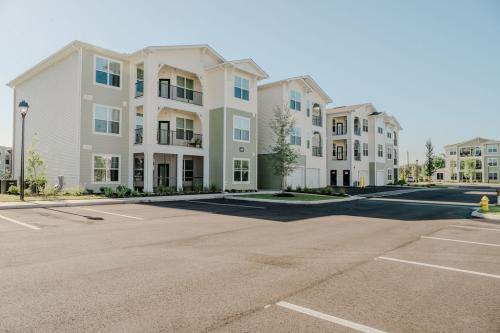 Apartments for rent in Ocala Three multi-story apartment buildings with balconies, light green and white exterior, and a surrounding empty parking lot under a clear sky. Aurora St. Leon Apartments in Ocala 2150 NW 21st Avenue | Ocala, FL 34475 (352) 233-4133